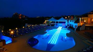 A pool area with lounge chairs and a tent.