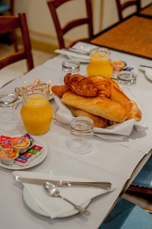 Ein Frühstückstisch mit Croissants, Saft und Beilagen.