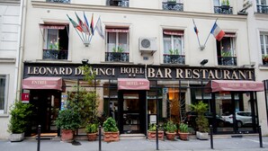 A hotel bar restaurant with multiple flags, potted plants, and a sign reading "LEONARD DE VINCI HOTEL BAR RESTAURANT". - Hôtel Léonard de Vinci (Paris)