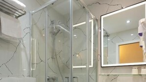 A modern bathroom with a glass shower enclosure, a white sink, and a marble-patterned wall. - Hôtel Léonard de Vinci (Paris)