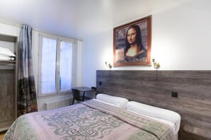 Ein Hotelzimmer mit Bett, Schreibtisch und einem Vorhangfenster.