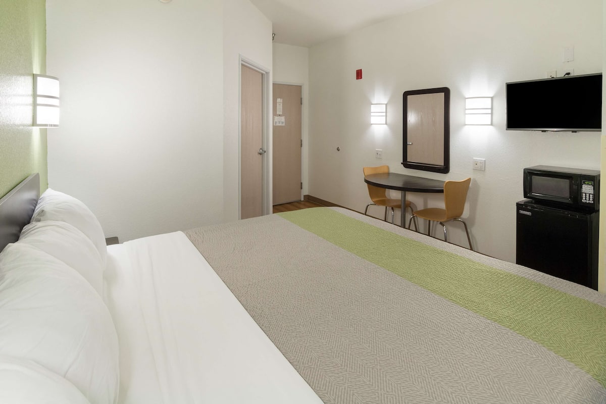Une chambre d’hôtel équipée d’un lit, d’un bureau avec une chaise, d’une télévision et d’un four à micro-ondes.