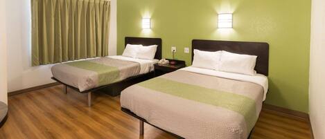 A hotel room with two beds, a green wall, and a window with curtains.