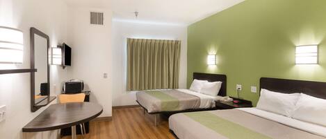 A hotel room with two beds, a desk, a chair, a television, and a window with curtains.