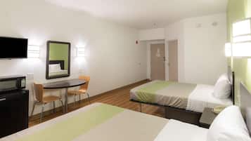 A hotel room with two beds, a desk with a chair, a television, and a microwave.