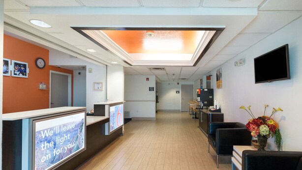 A reception area with a digital display, a clock, and a TV mounted on the wall. - Motel 6 Hillsboro, TX (Hillsboro)