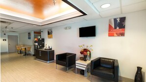 A lobby with a reception desk, seating area, and a television on the wall. - Motel 6 Hillsboro, TX (Hillsboro)