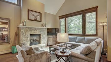 A spacious living room with a stone fireplace, large windows, and a modern sofa set.