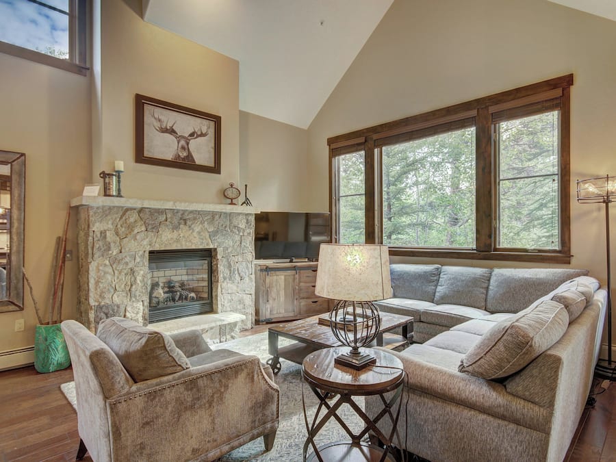 A spacious living room with a stone fireplace, large windows, and a modern sofa set.