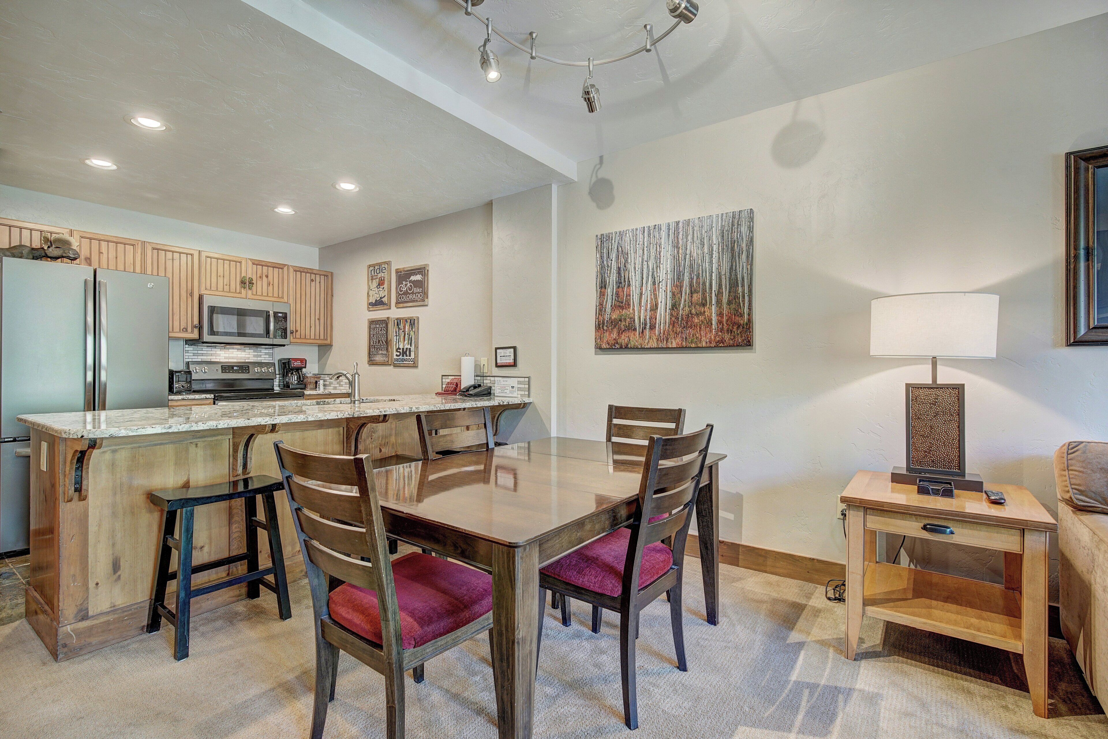 Una cocina moderna con una isla central, armarios de madera y un comedor con sillas y una mesa.