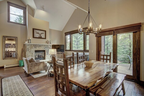 A spacious dining area with a large wooden table, multiple chairs, and a fireplace.