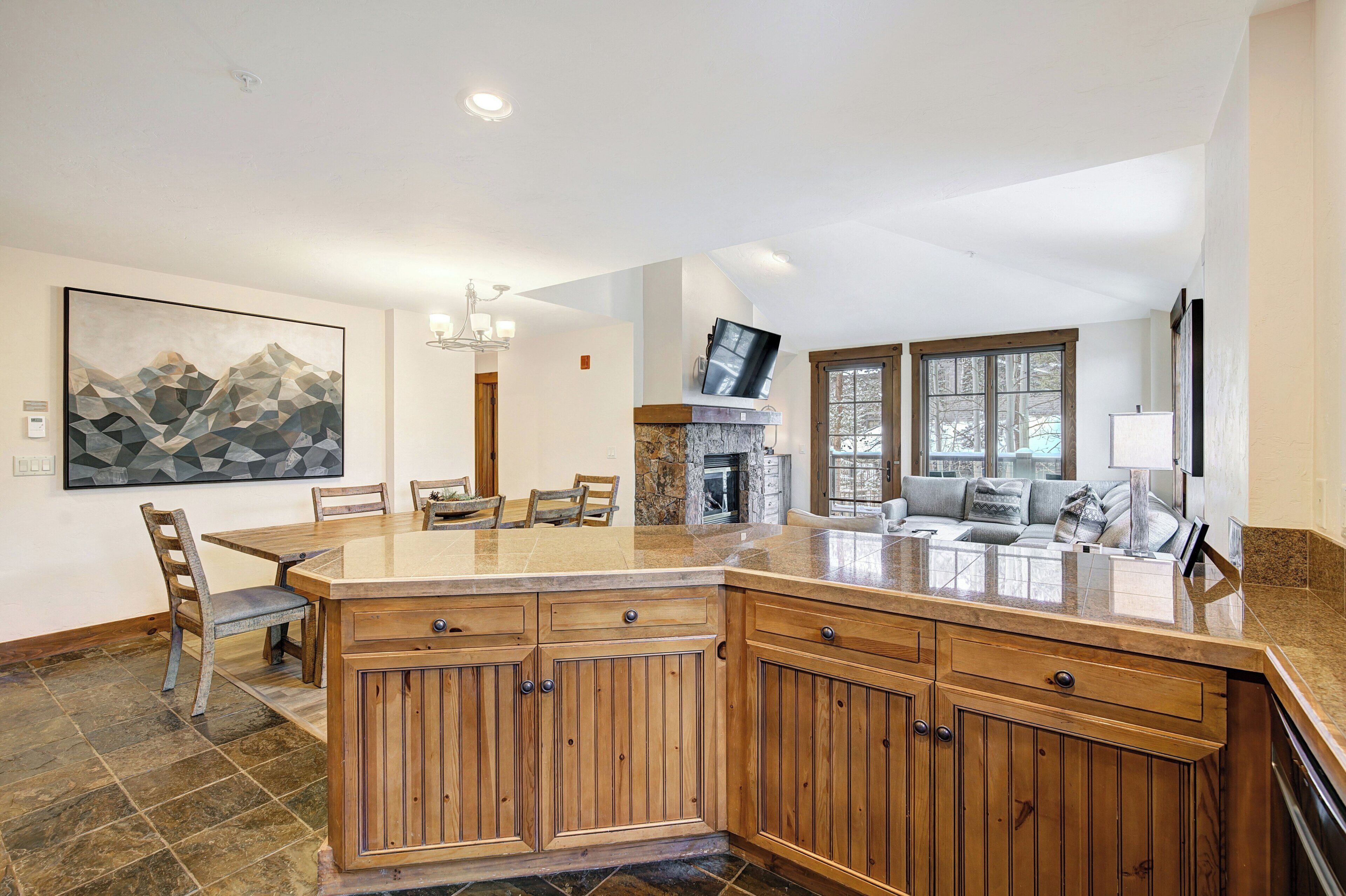 A spacious kitchen with a large island, wooden cabinets, and a dining area with chairs.