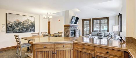 A spacious kitchen with a large island, wooden cabinets, and a dining area with chairs.