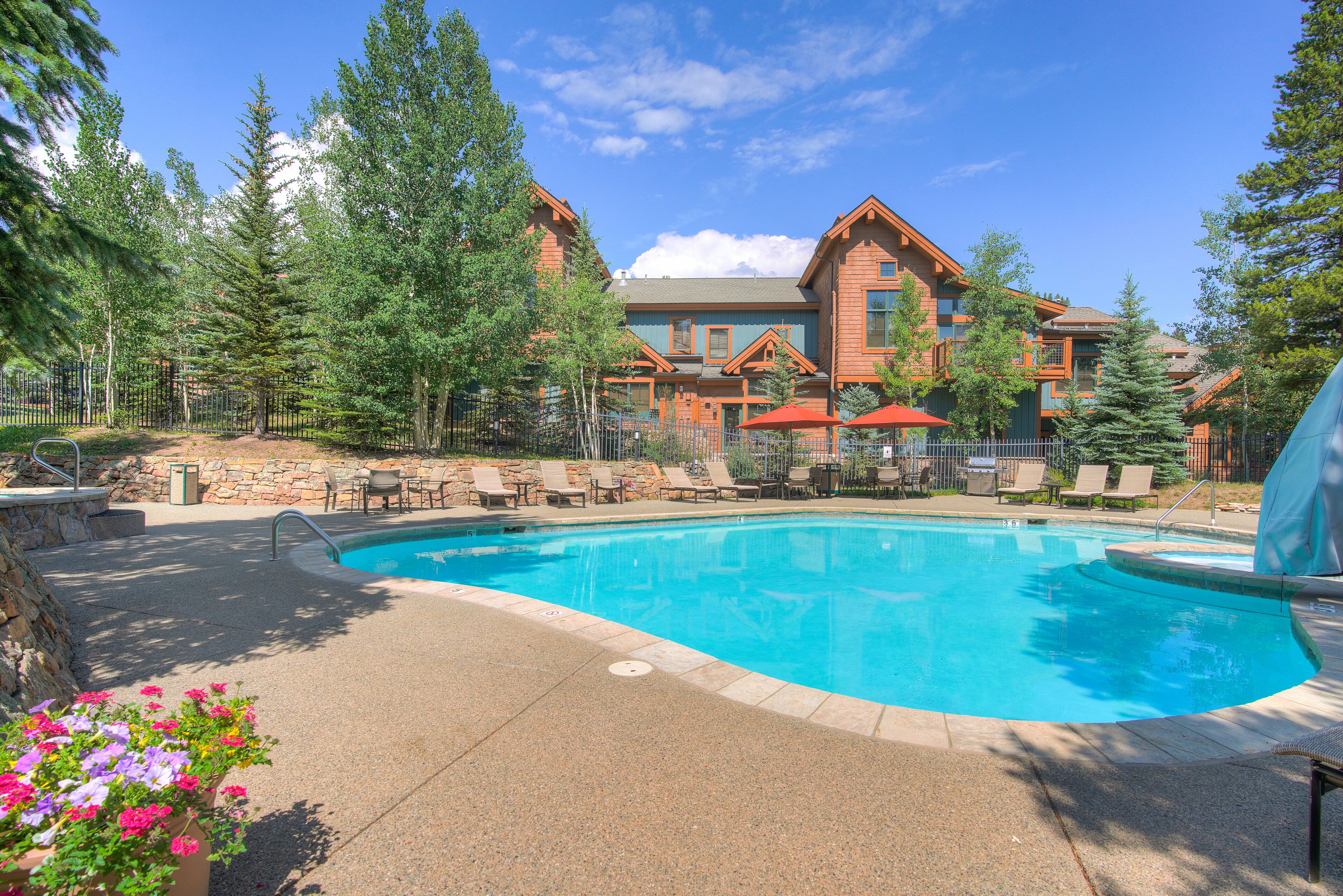 A pool area with lounge chairs and a building with a wooden facade in the background.
