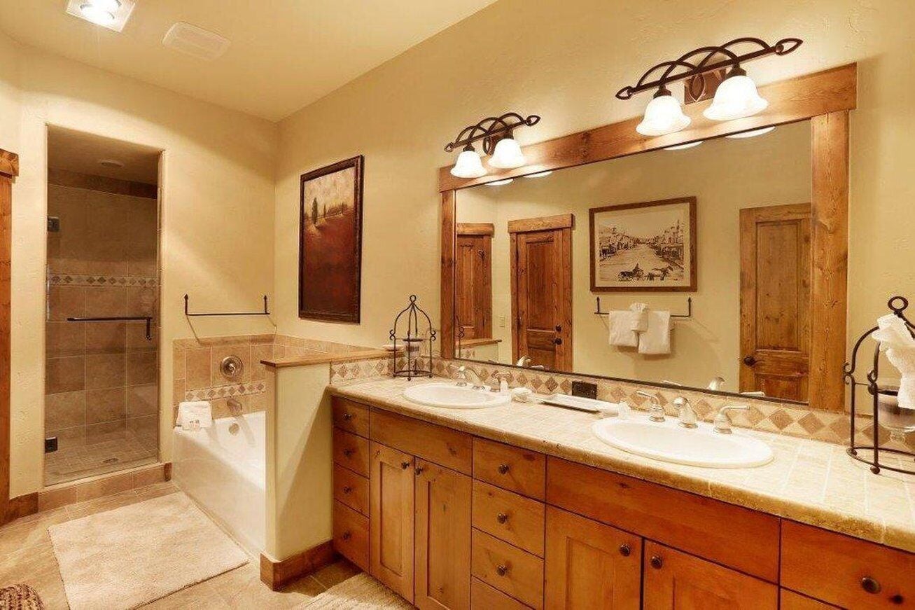 Une salle de bain avec un meuble-lavabo à deux vasques, un grand miroir et un espace douche.