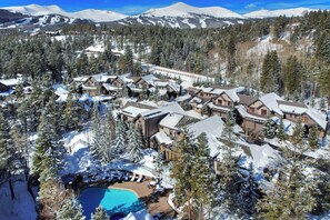 A snow-covered resort with multiple buildings, a swimming pool, and a ski slope in the background. - Mountain Thunder Lodge, A Vail Resorts Property (Breckenridge)