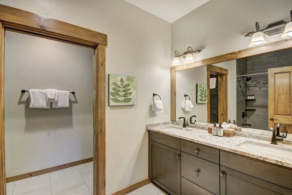 A bathroom with a wooden door, a sink with a mirror, and a towel rack. - Mountain Thunder Lodge, A Vail Resorts Property (Breckenridge)