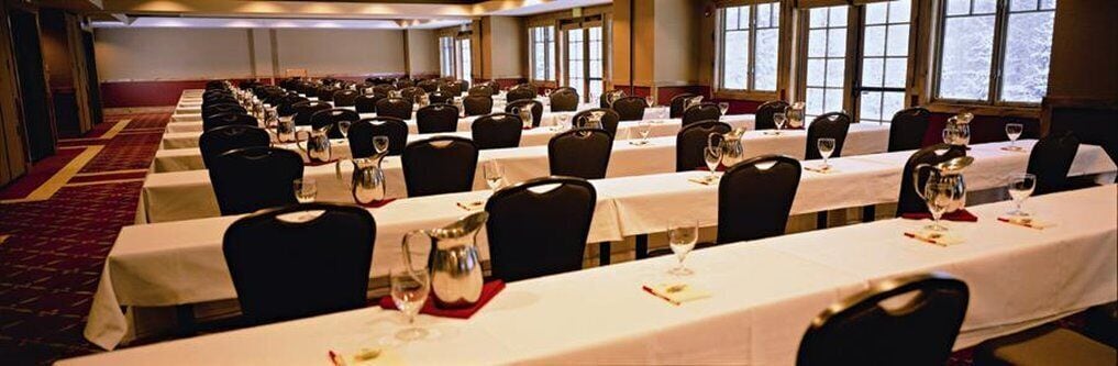 A banquet hall with rows of tables set for dining, each with chairs and table settings.