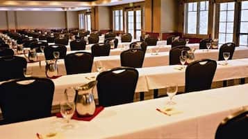 A banquet hall with rows of tables set for dining, each with chairs and table settings.