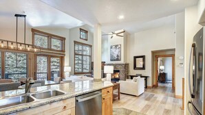 A spacious kitchen with granite countertops, a dishwasher, and a large island. There are multiple windows providing natural light and views of the outdoors.