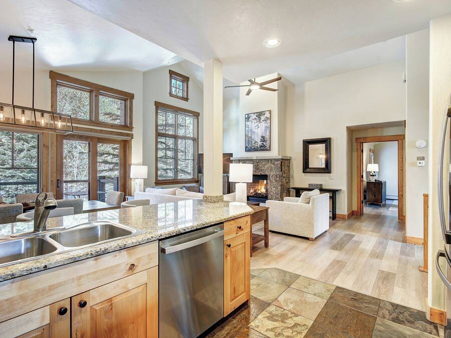 A spacious kitchen with granite countertops, a dishwasher, and a large island. There are multiple windows providing natural light and views of the outdoors.