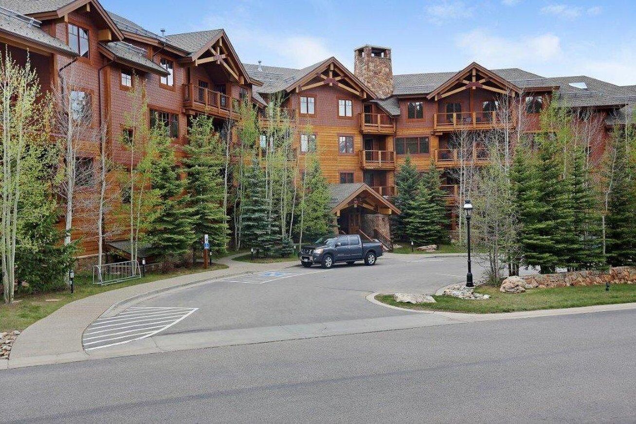 A large lodge with multiple floors, a central entrance, and a parking area.