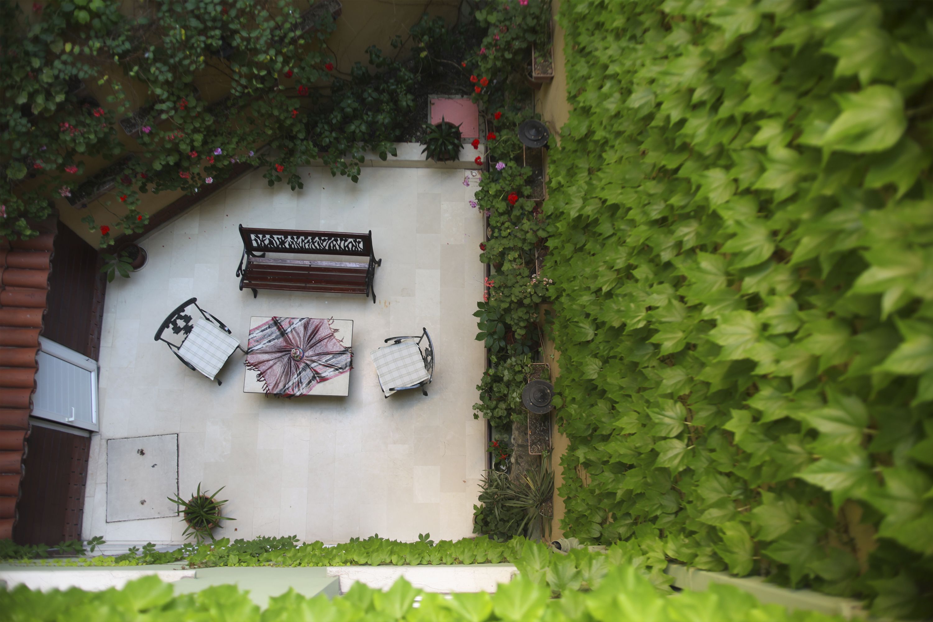 A courtyard with a bench, a table, and potted plants.