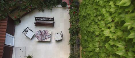 A courtyard with a bench, a table, and potted plants.