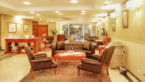 A spacious lobby with a leather sofa, armchairs, a wooden coffee table, and a patterned rug.