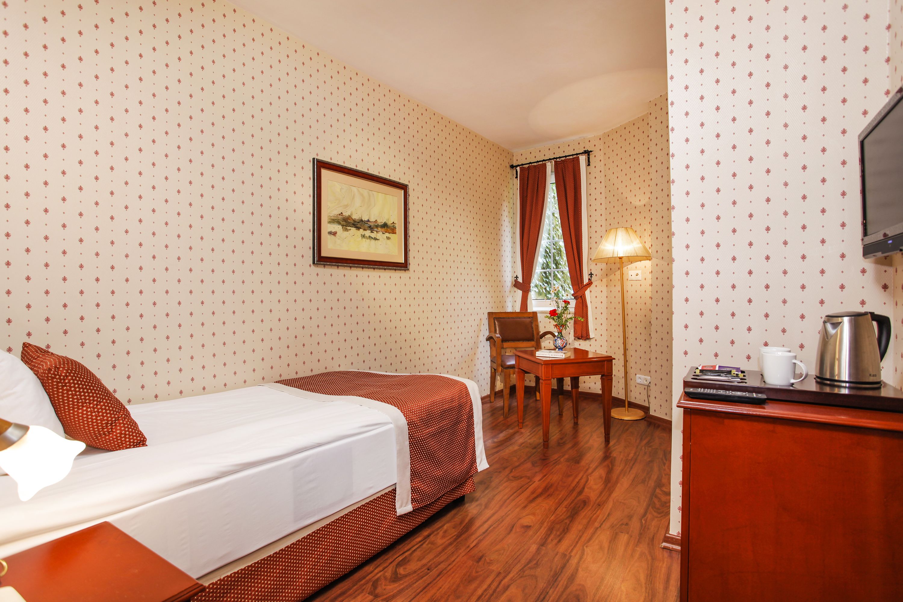 Une chambre d’hôtel avec deux lits, un bureau, une chaise, une lampe, une télévision et une machine à café.
