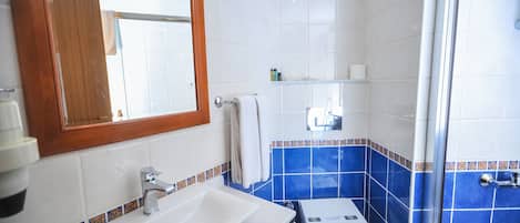 Un baño con lavamanos blanco, inodoro y zona de ducha.