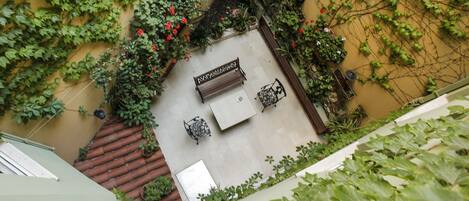 An outdoor patio area with a bench, potted plants, and a tiled floor.