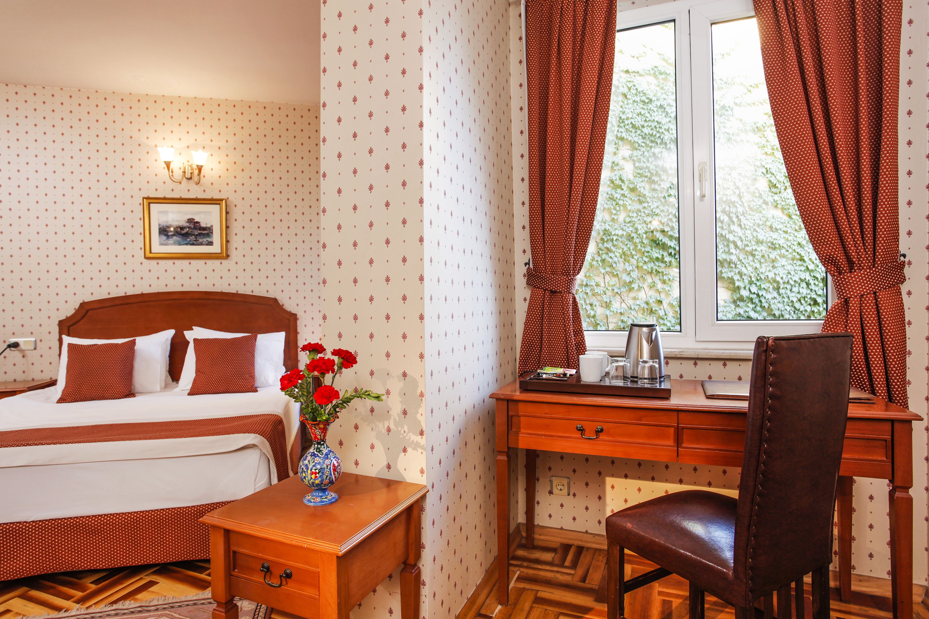 Une chambre à coucher avec un lit, un bureau en bois, une chaise et une fenêtre avec des rideaux.