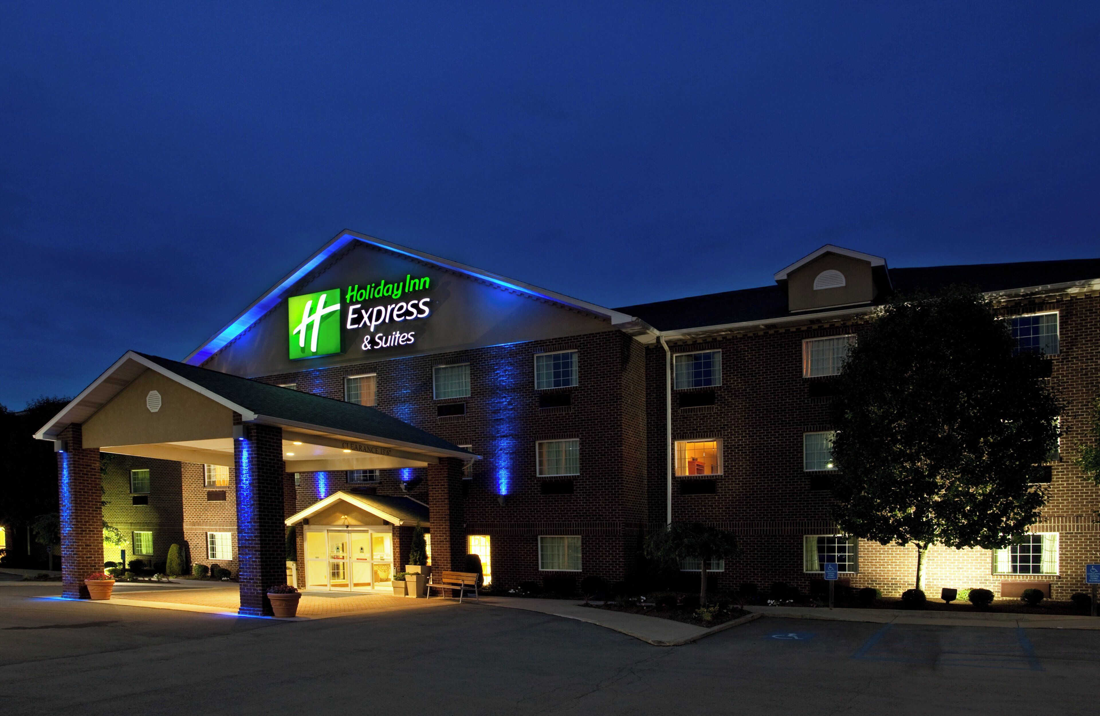 A Holiday Inn Express & Suites building with a brick facade and a well-lit entrance.