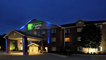 A Holiday Inn Express & Suites building with a brick facade and a well-lit entrance.