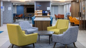 A modern lounge area with a coffee station, seating arrangements, and a sign promoting coffee. - Holiday Inn Express & Suites Center Township by IHG (Monaca)