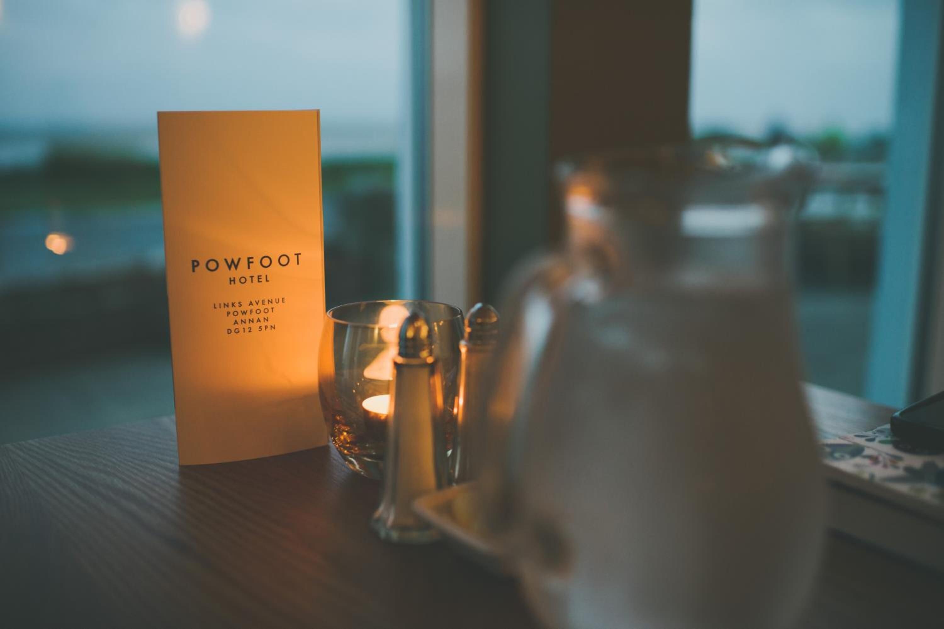 A hotel sign, a candle, and a pitcher on a table.