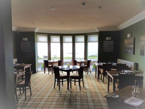 A dining area with a checkered floor, multiple tables, and chairs. - Powfoot Hotel (Annan)