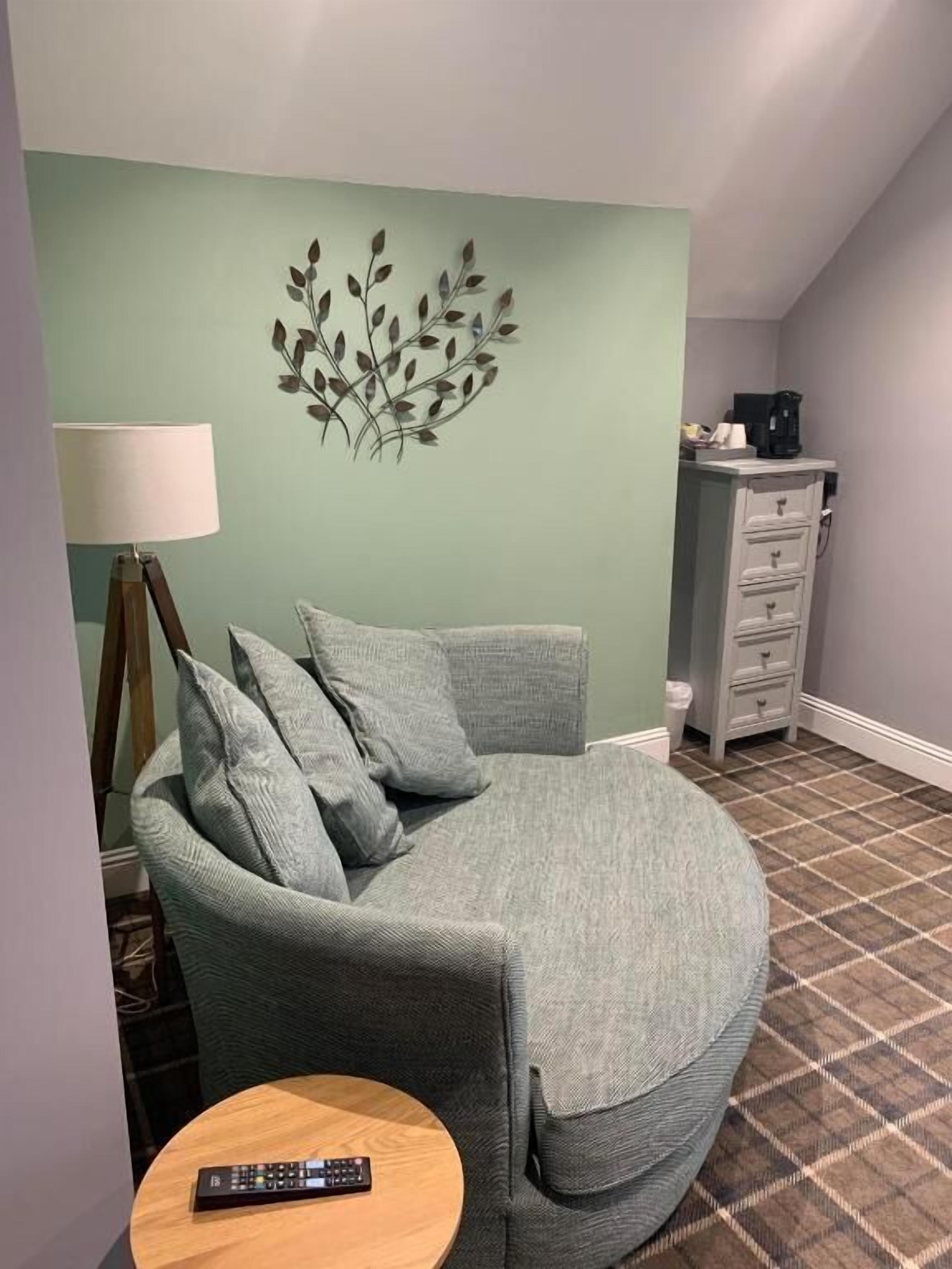 A living room with a sofa, a lamp, a remote control, and a wall art piece.