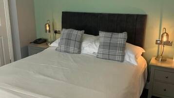A neatly made bed with a dark headboard, two bedside tables with lamps, and a checkered floor pattern.