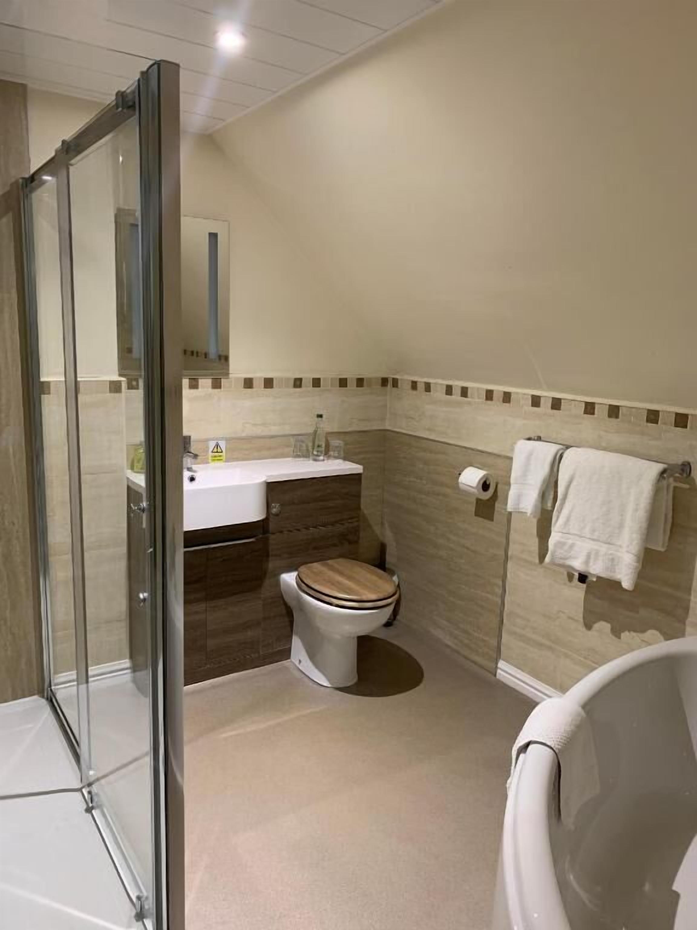 A bathroom with a glass shower enclosure, a toilet, a sink, and a bathtub.