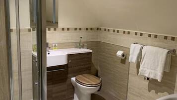 A bathroom with a glass shower enclosure, a toilet, a sink, and a bathtub.