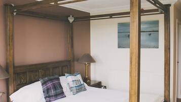 A four-poster bed with a wooden frame, white bedding, and two pillows.