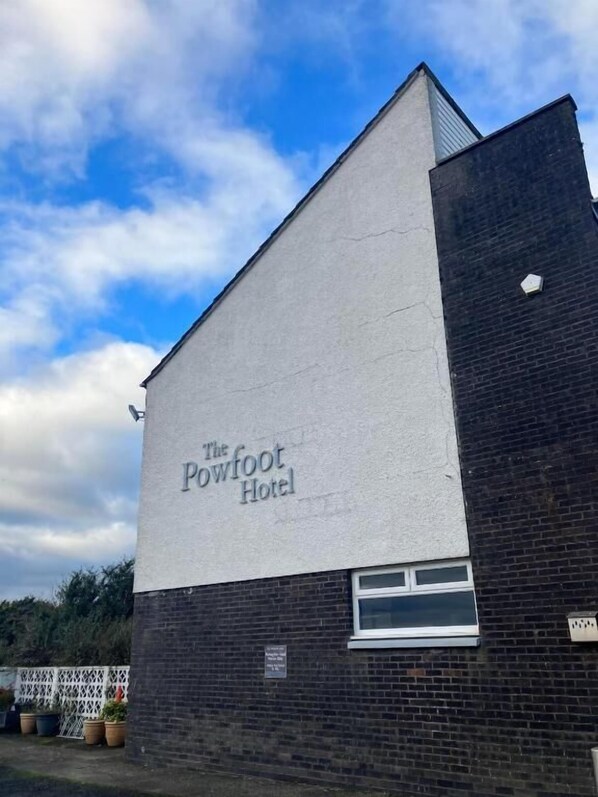 A building with a sign reading 'The Powfoot Hotel' on a white wall.