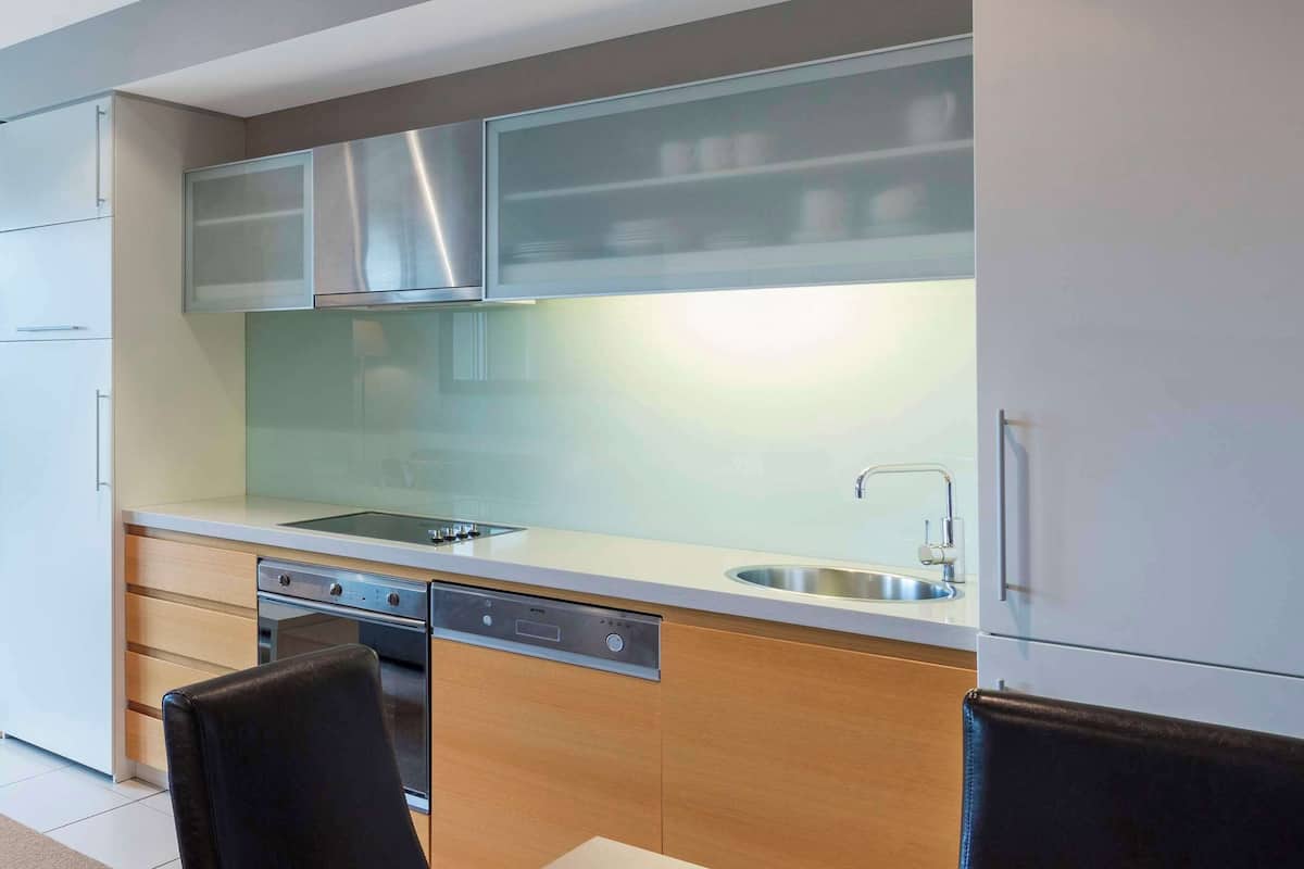 Een moderne keuken met een inbouwvaatwasser, roestvrijstalen apparatuur en een groot raam boven de gootsteen.