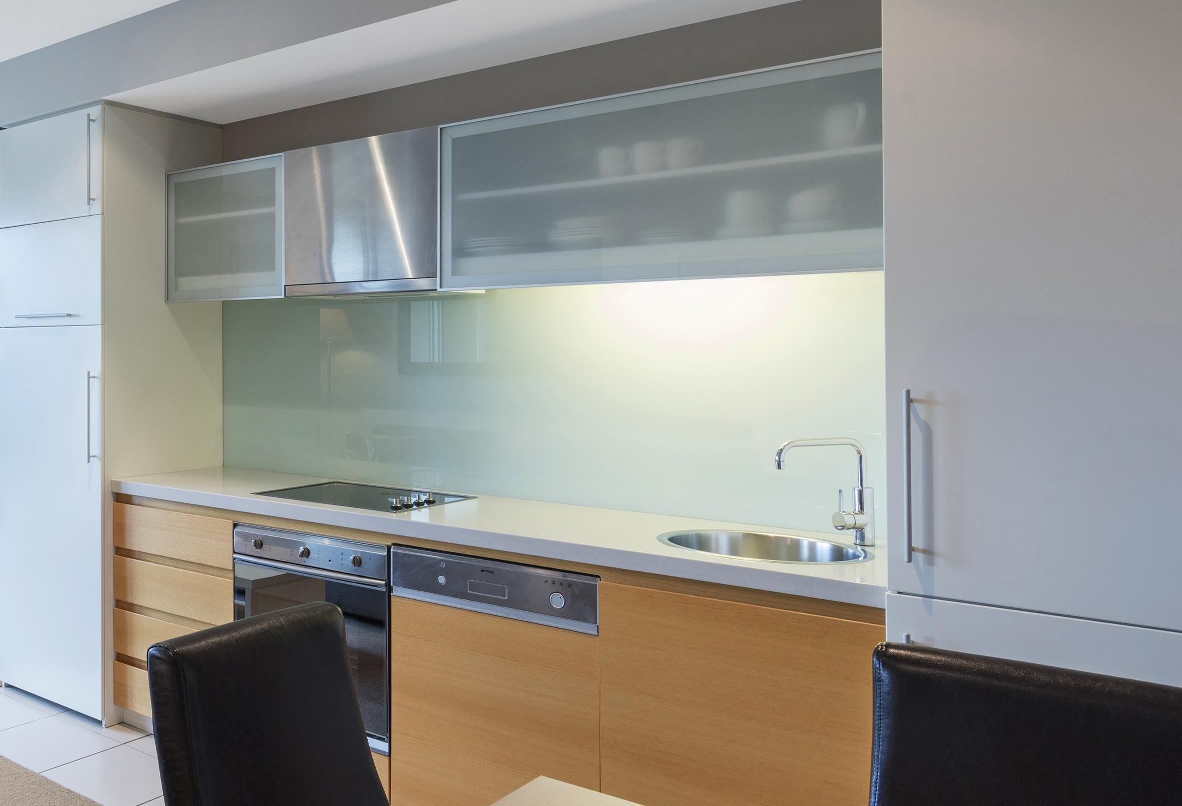 A modern kitchen with a stainless steel range hood, a double sink, and a dishwasher.