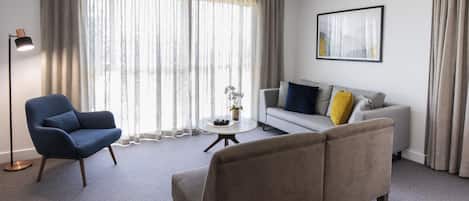A modern living room with a sofa, armchair, and a coffee table.