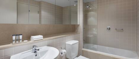 Een moderne badkamer met een wastafel, toilet en douchecabine met glazen wanden.