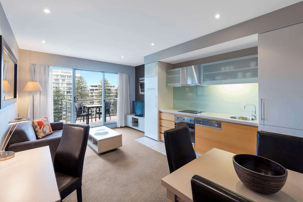 Een moderne hotelkamer met balkon, eethoek en kitchenette.