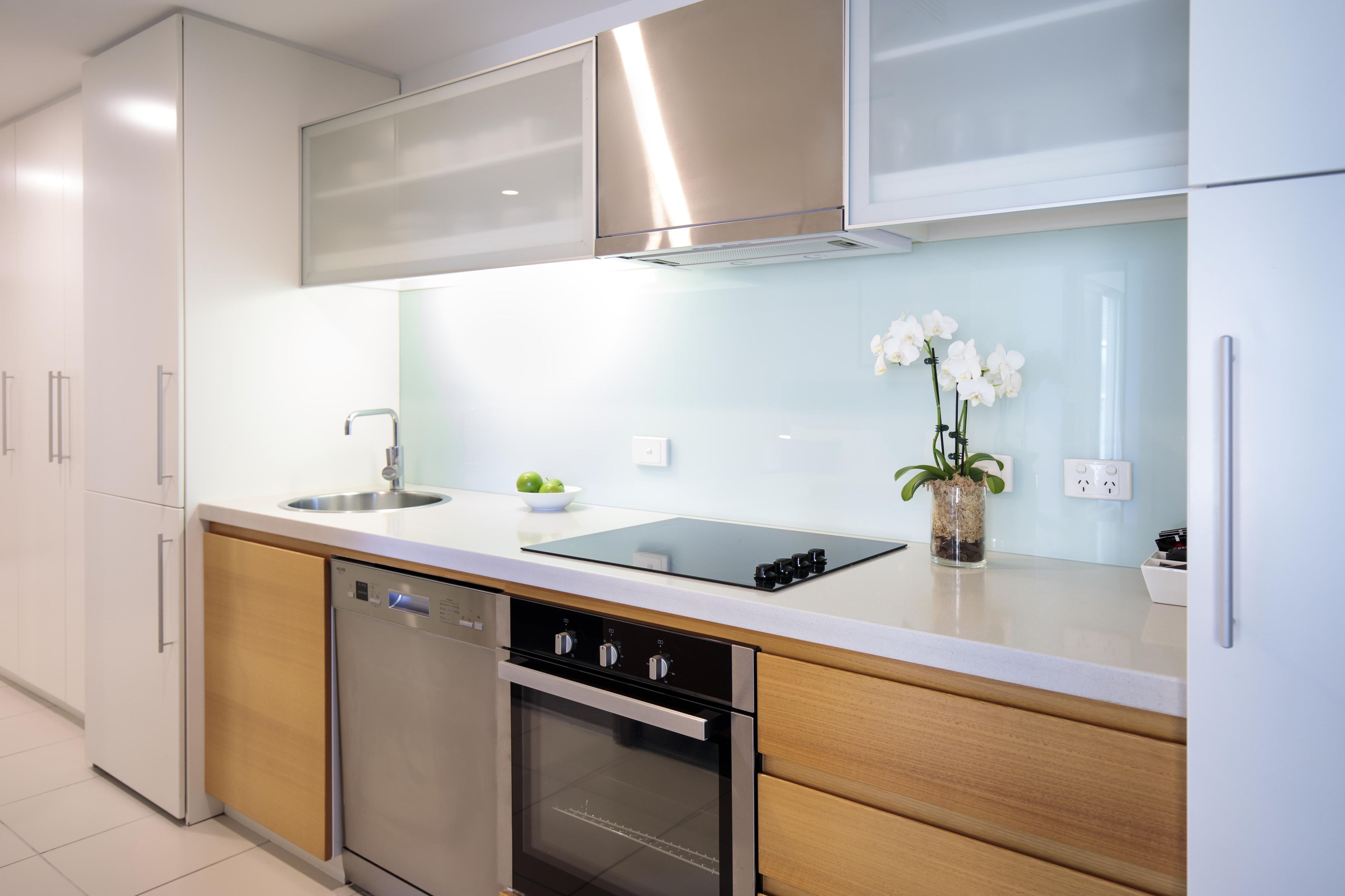 Una cocina moderna con electrodomésticos de acero inoxidable, lavavajillas y un lavamanos.